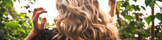 Woman with shiny long curly hair in the sunshine, in a forrest about to take some multivitamins Vigor Essential