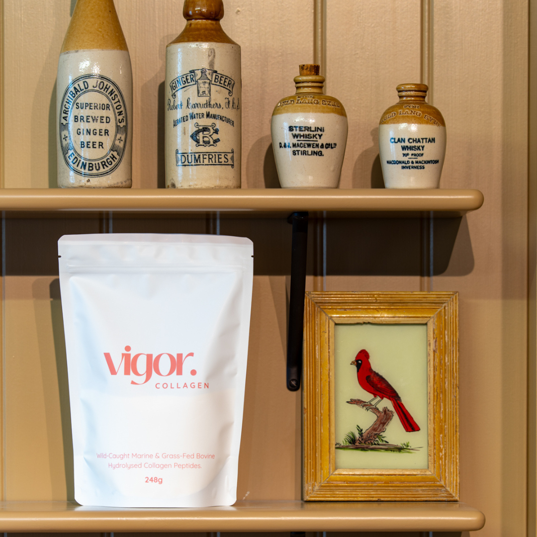 Shelf with vigor collagen package, framed picture of a cardinal, and vintage-style bottles.