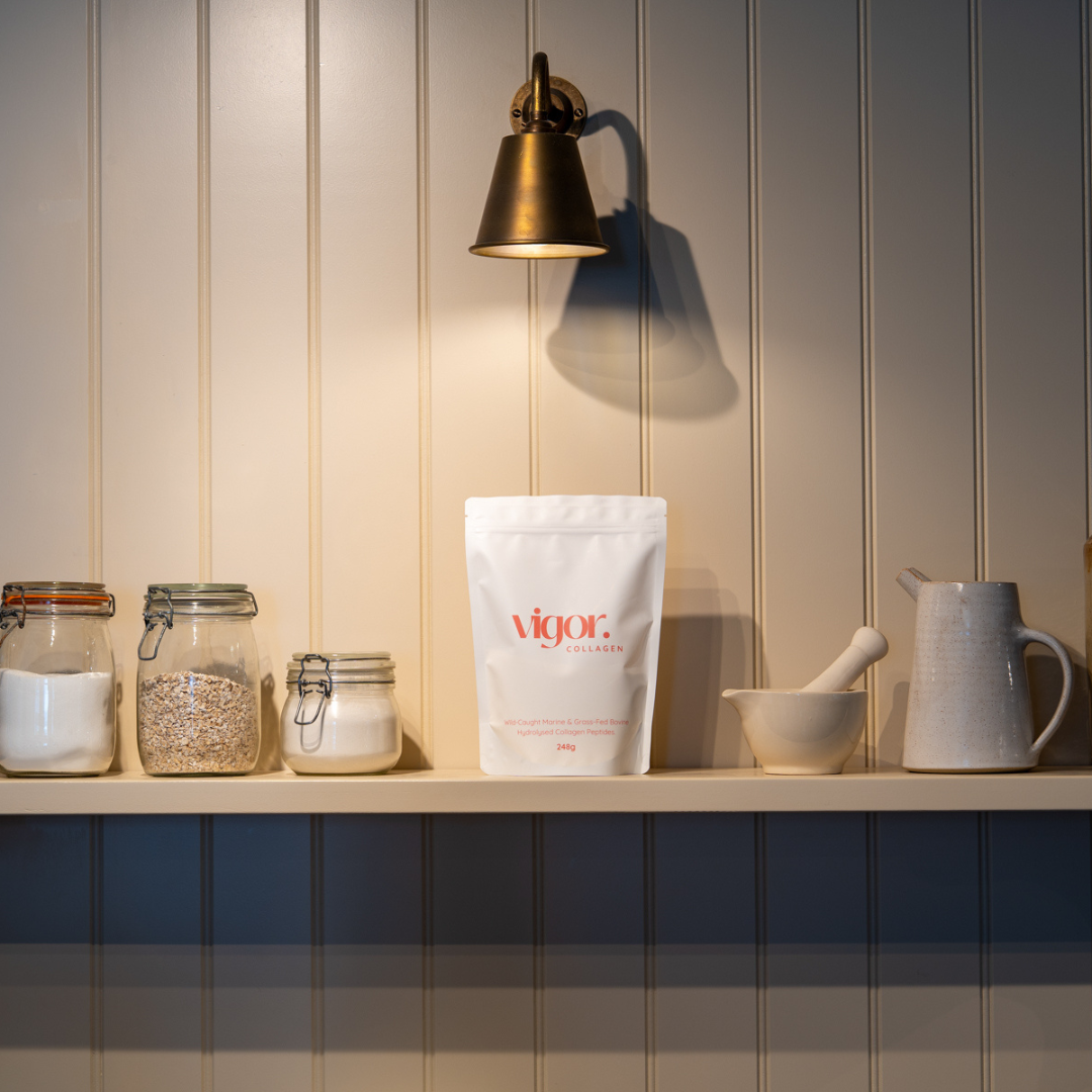 Vigor Collagen bag on a shelf with jars and a pitcher against a wooden panel wall.