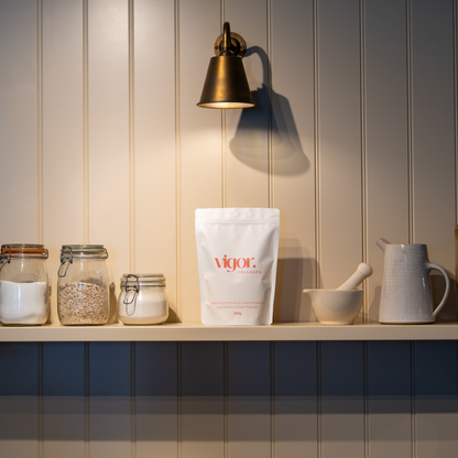 Vigor Collagen bag on a shelf with jars and a pitcher against a wooden panel wall.