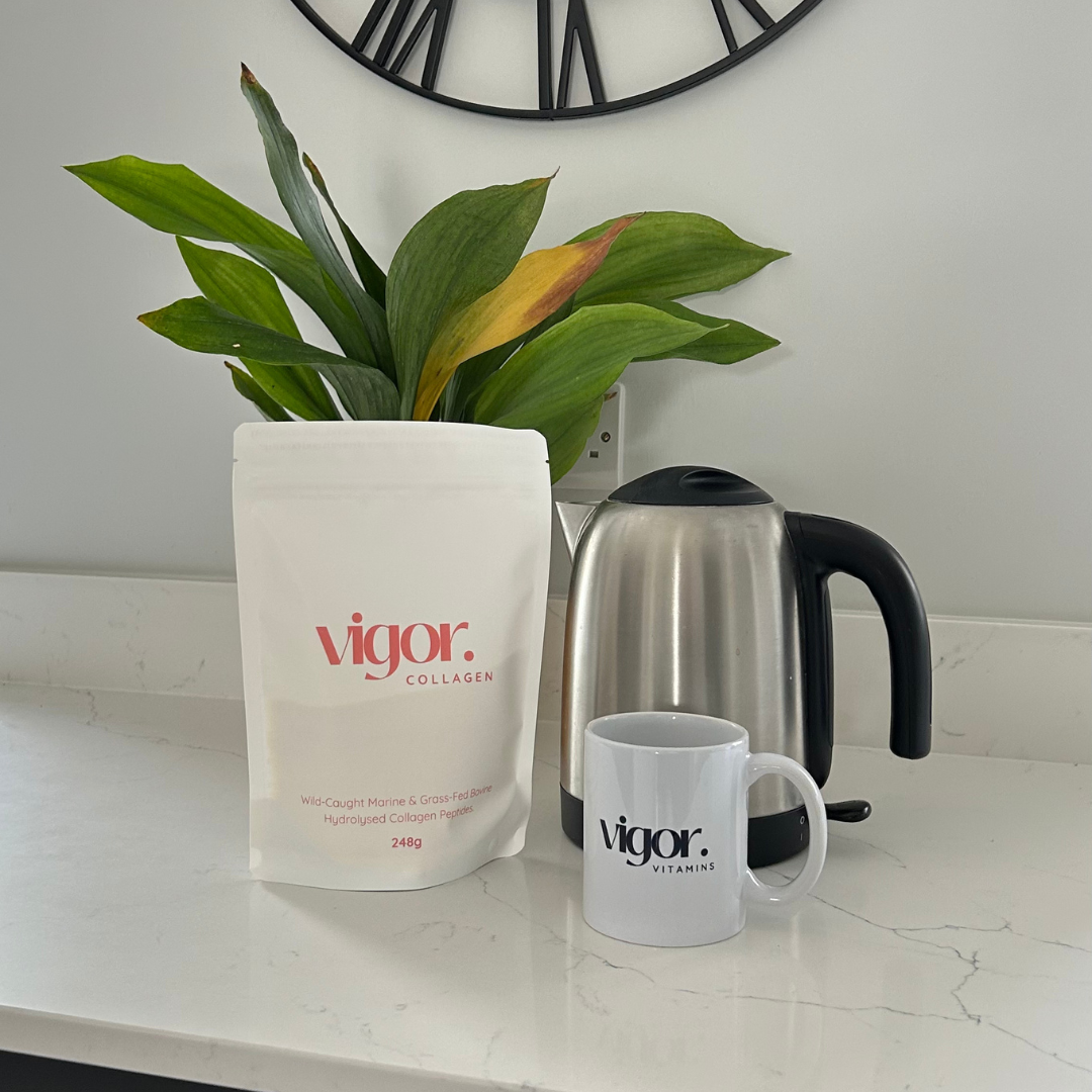 Vigor collagen powder bag and mug on a kitchen counter with a plant and kettle in the background.